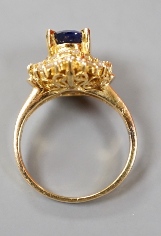 A modern 750 yellow metal, sapphire and diamond set oval cluster ring, size H, gross weight 4.6 grams.